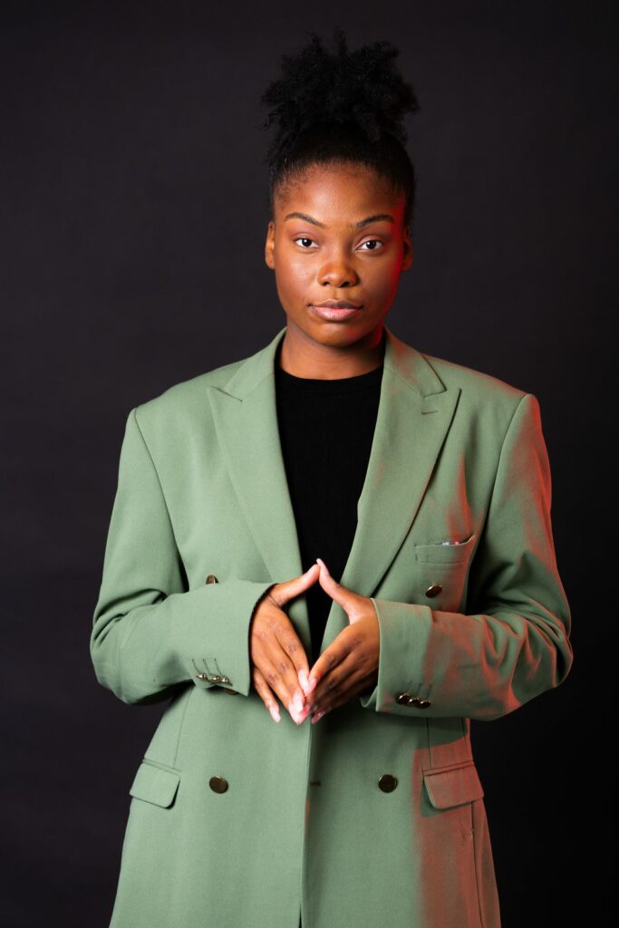 Portrait corporate d'une femme en blazer vert sur fond noir
